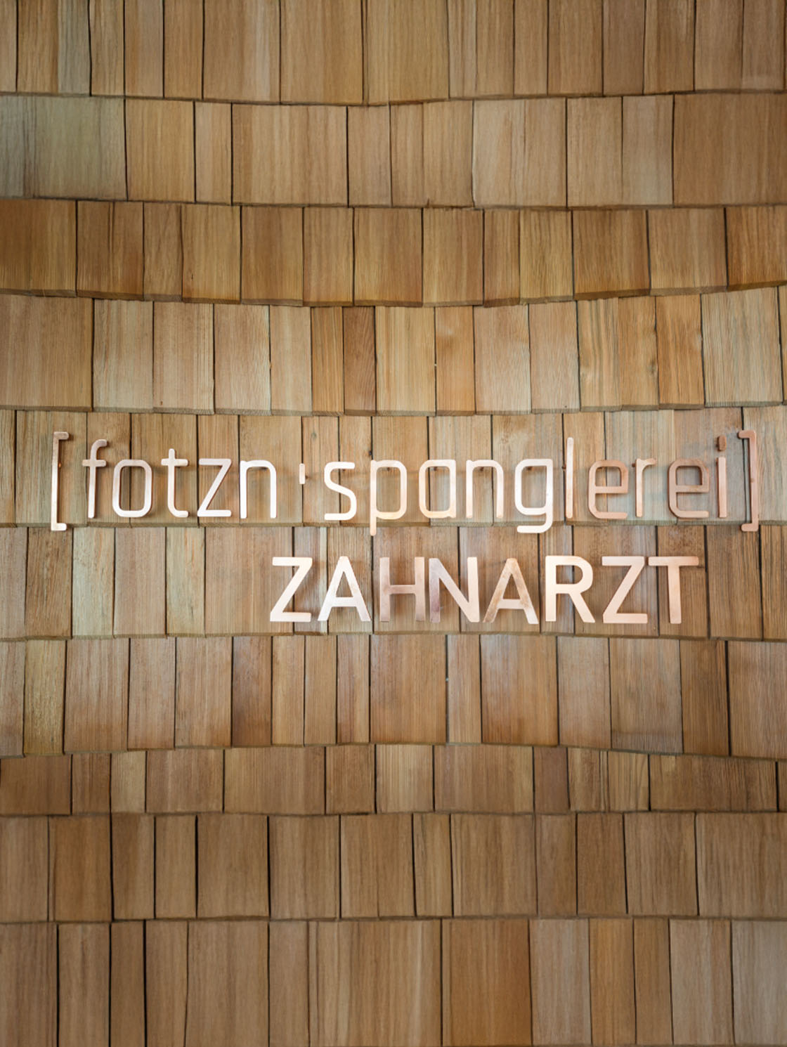 Holzwand mit fotzn'spanglerei Logo in Praxis