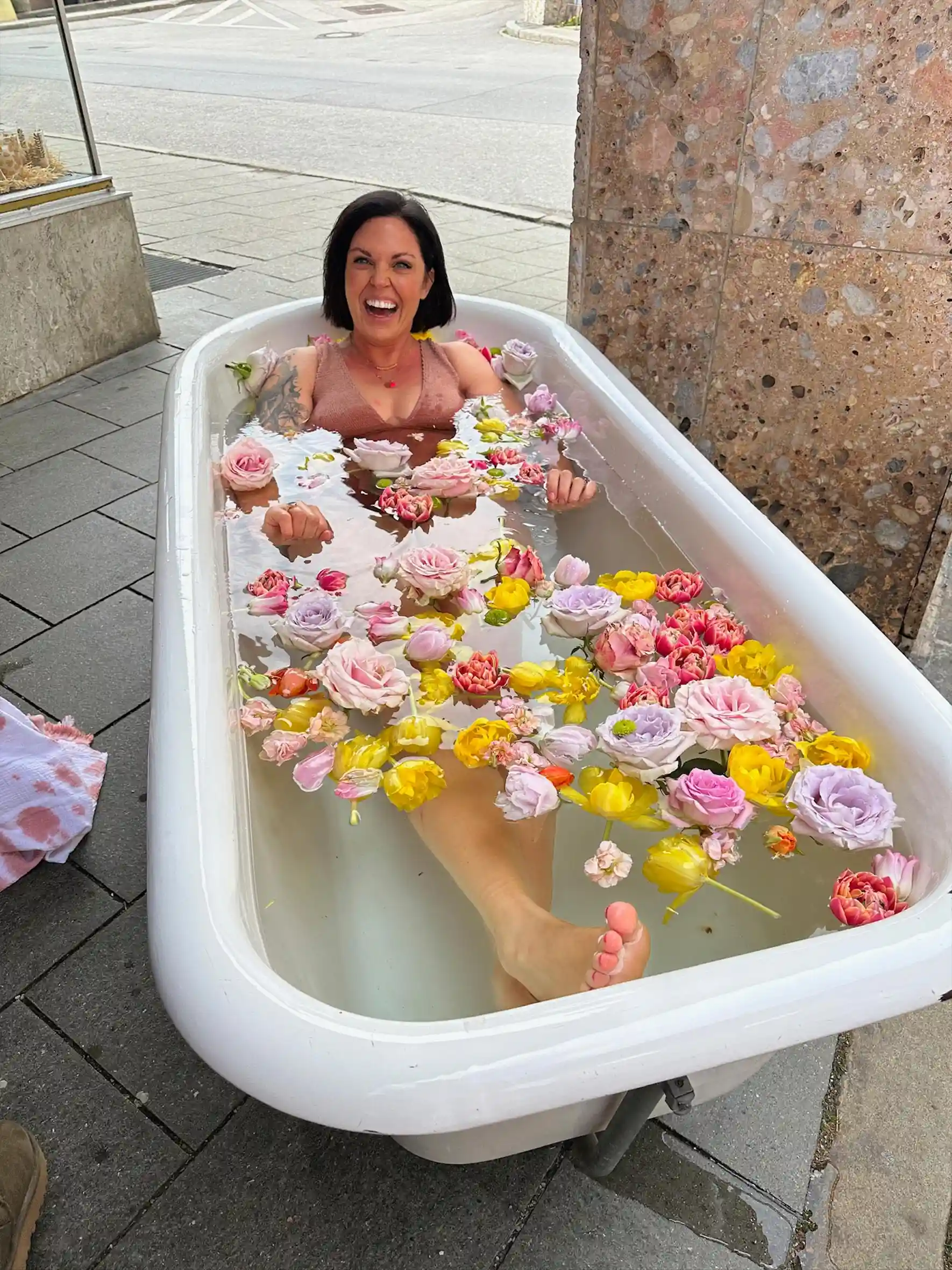 Dr. Petra Sophie Volz in Badewanne in Stadt mit Blumen